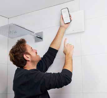 Szerelő a falba épített ELS NFC előlapjához tartja a telefonját (gyári fotó)